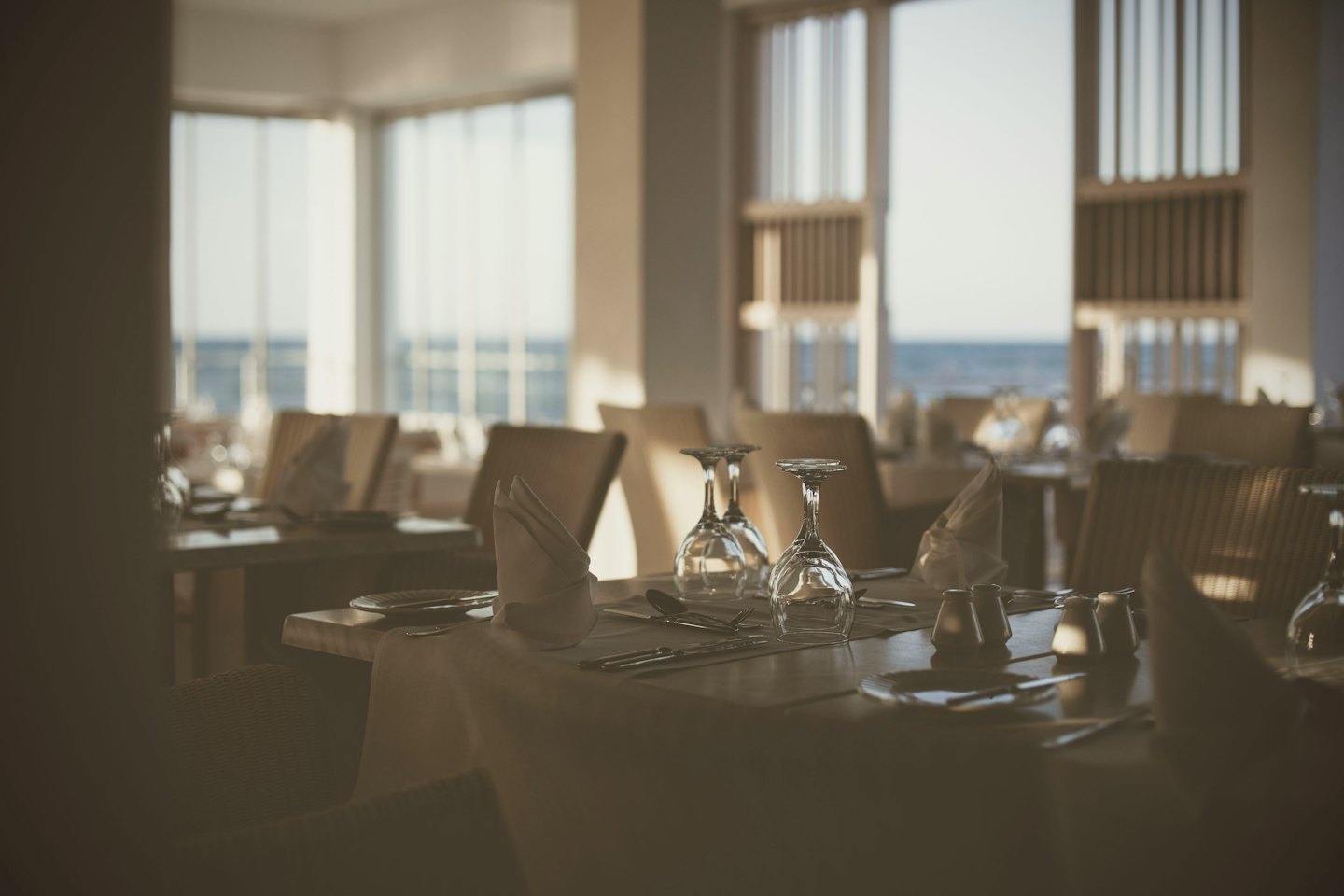 Ustawione stoły czekają na gości w słonecznej restauracji.