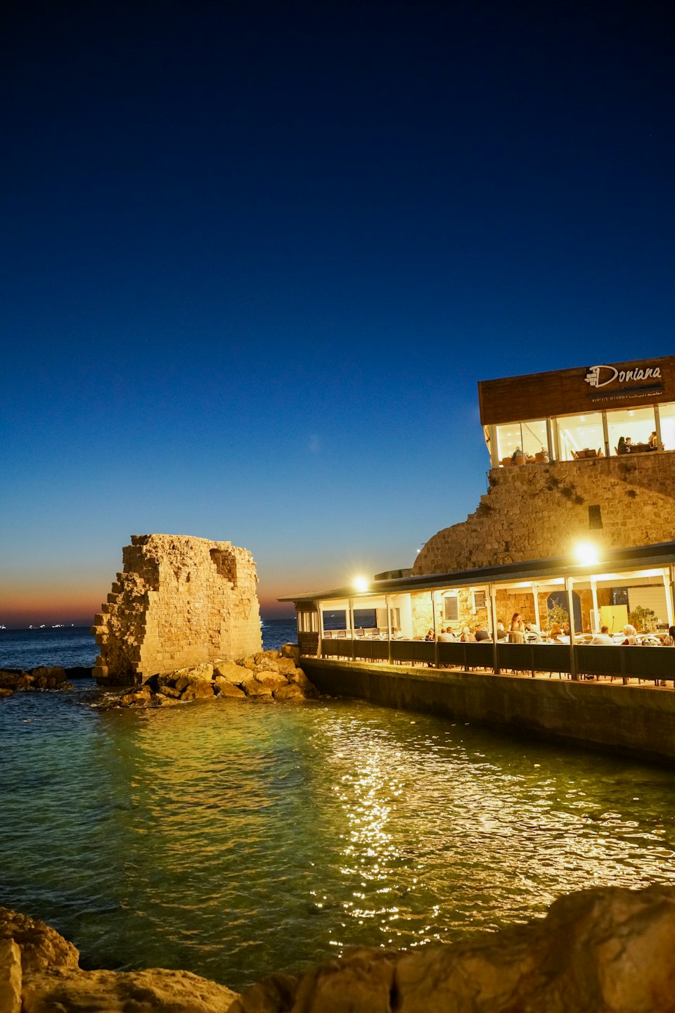 Restauracja nad wodą świeci obok starożytnych kamiennych ruin.