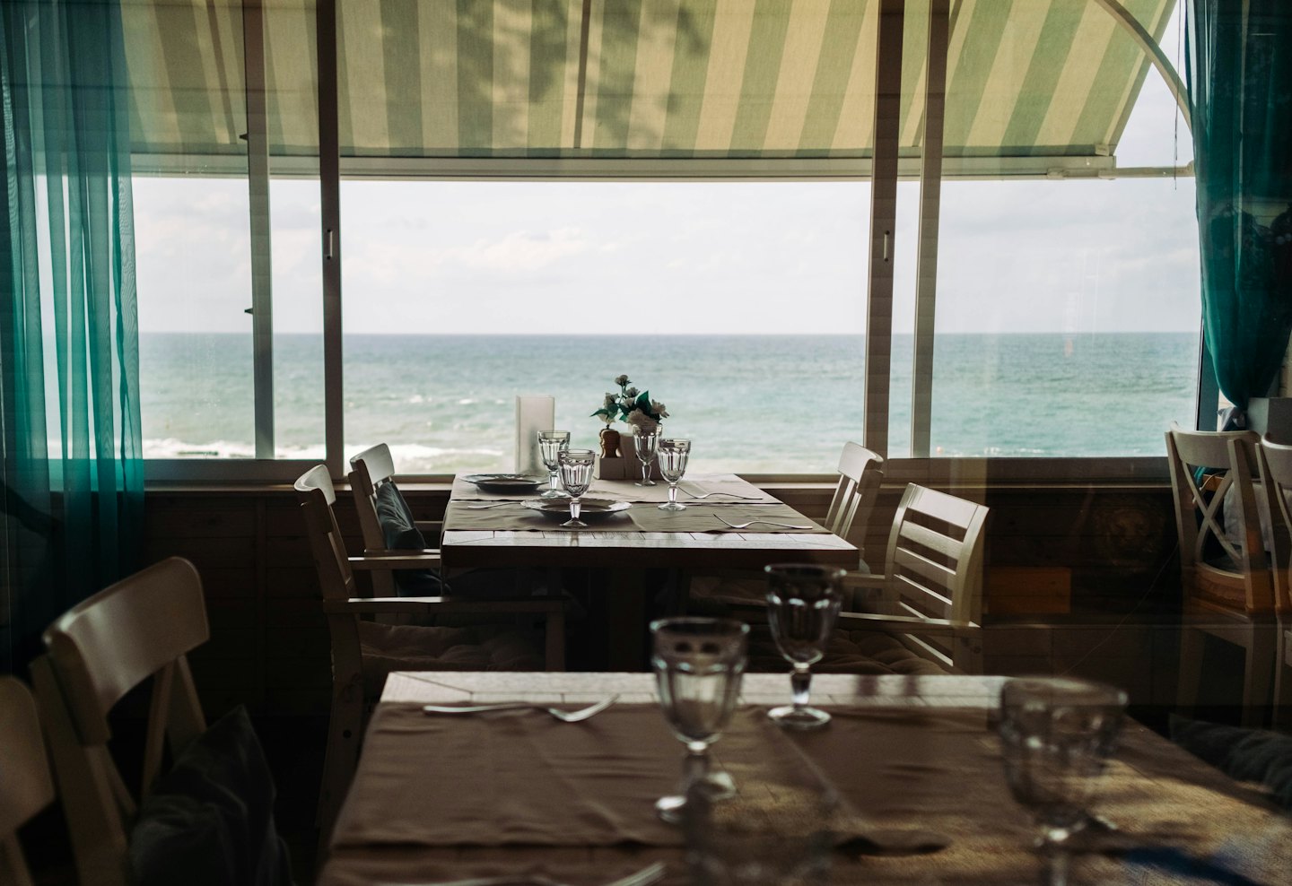 Restauracyjne stoliki z widokiem na ocean przez duże okna.
